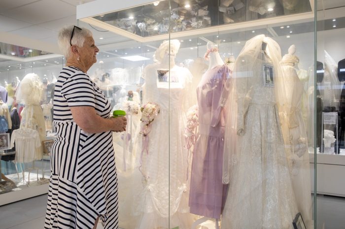 A visitor looking closely at the wedding dresses through the glass