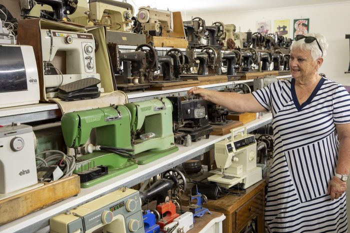 A volunteer beside a long wall of vintage sewing machines