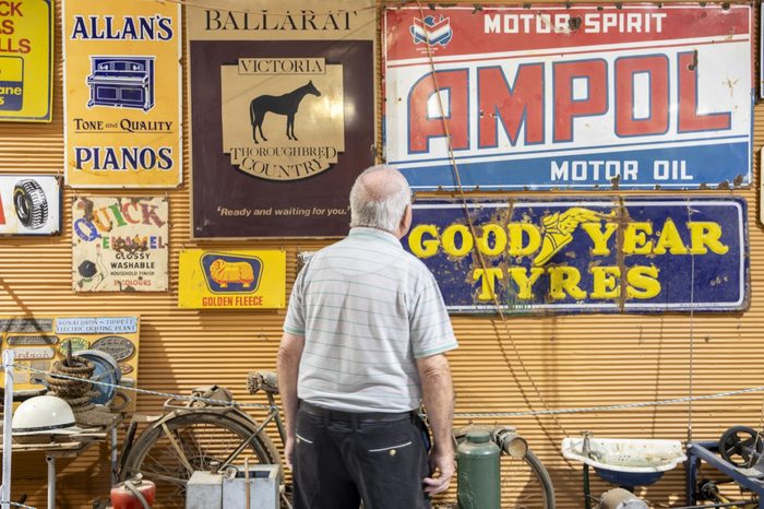 A visitor in front of a wall of enamel advertising signs