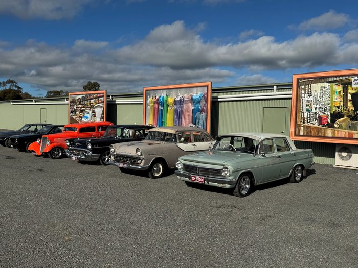 Classic cars parked outside the museum below its large display panels