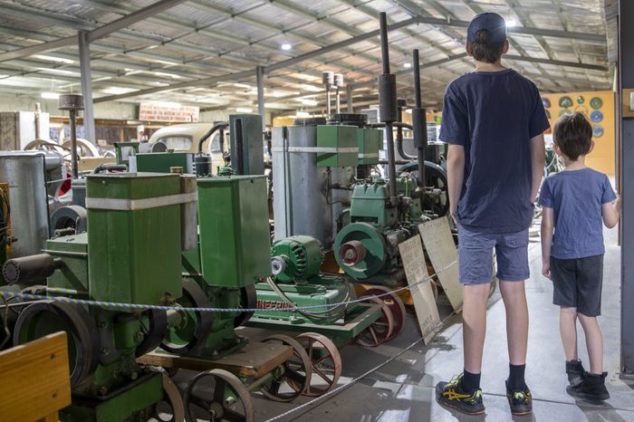 Two boys looking at a row of restored stationary engines