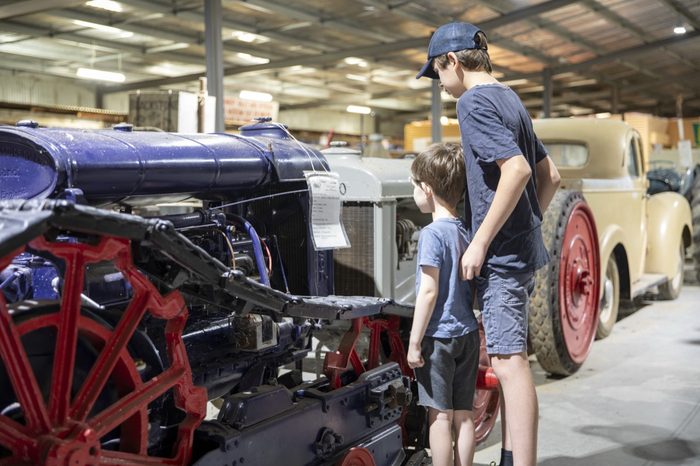 Children beside a restored veteran car with red spoked wheels