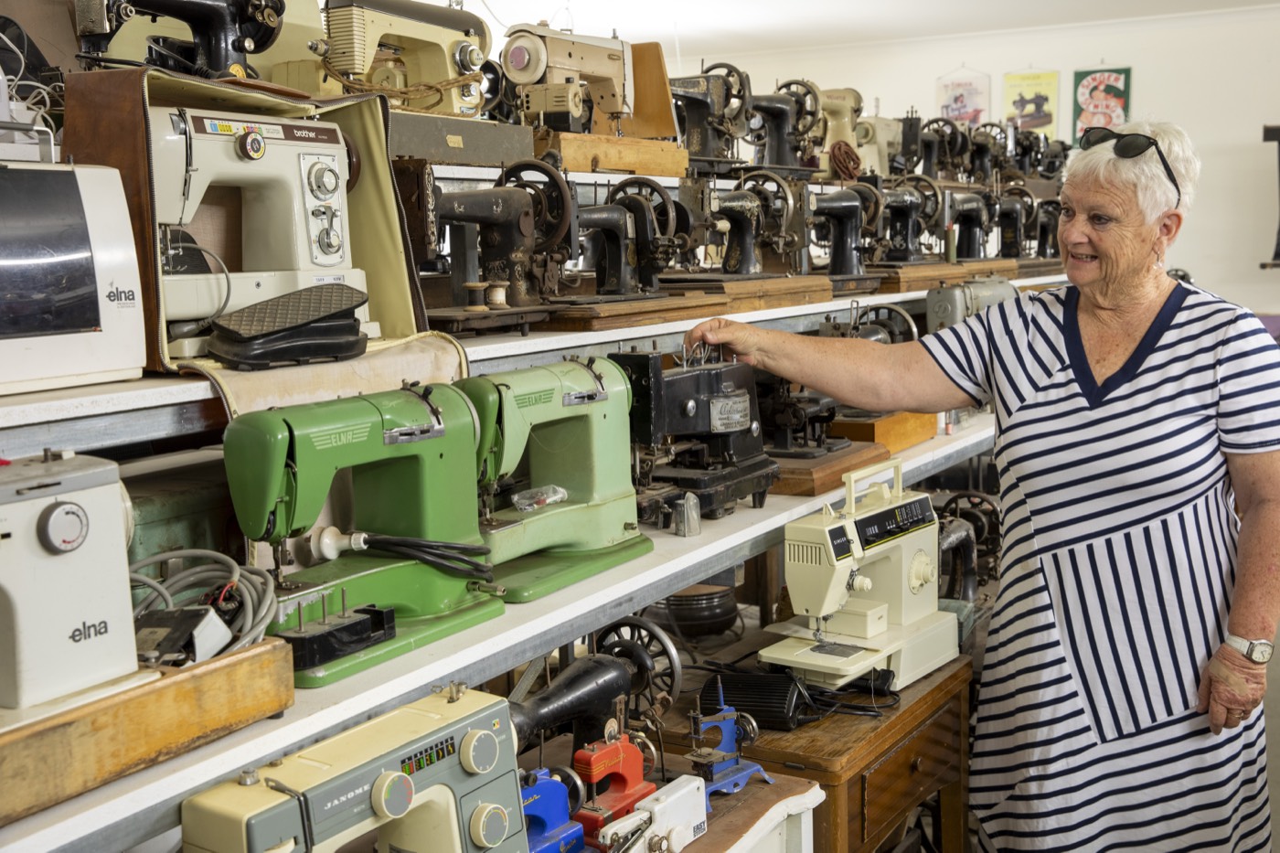 A volunteer beside a wall of vintage sewing machines