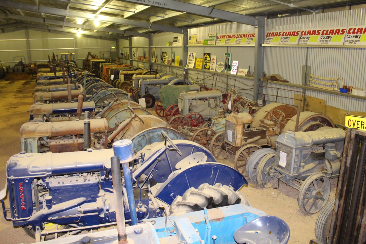 A long row of vintage tractors in the machinery shed